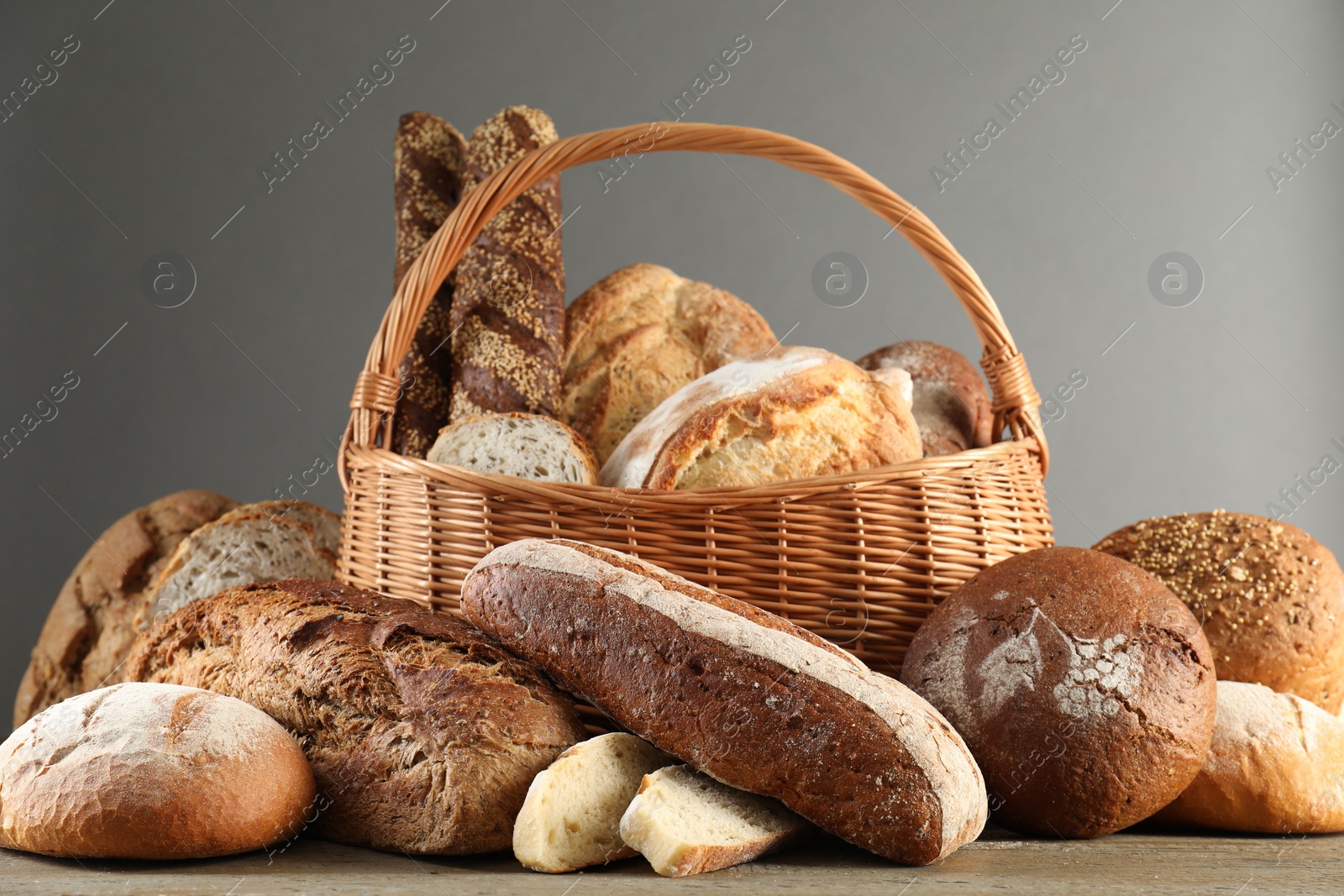 Photo of Wicker basket with different types of fresh bread on wooden table