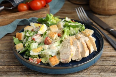 Photo of Delicious Caesar salad in bowl on wooden table