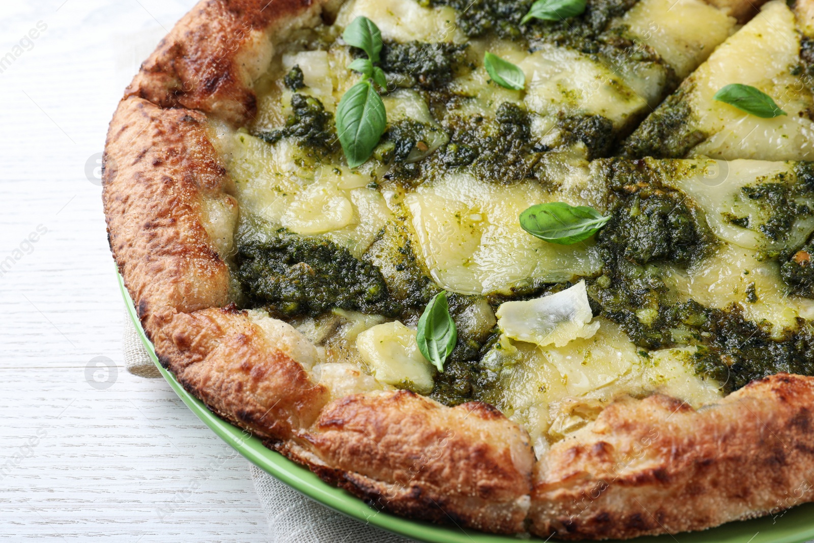 Photo of Delicious pizza with pesto, cheese and basil on white wooden table, closeup