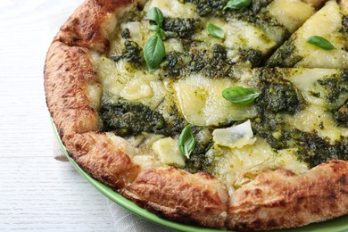 Delicious pizza with pesto, cheese and basil on white wooden table, closeup