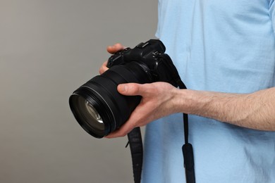 Photo of Photographer holding camera on grey background, closeup