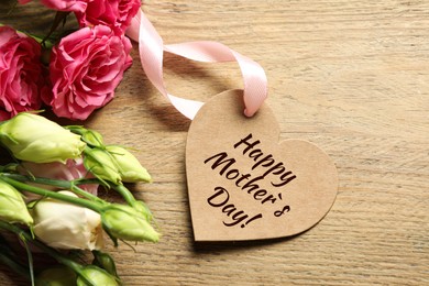 Happy Mother's Day. Heart shaped greeting label and beautiful flowers on wooden table