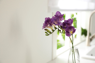 Photo of Beautiful purple freesia flowers on countertop in kitchen, closeup. Space for text