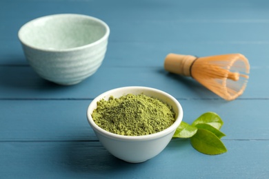 Photo of Bowl with matcha tea and green leaves on wooden table