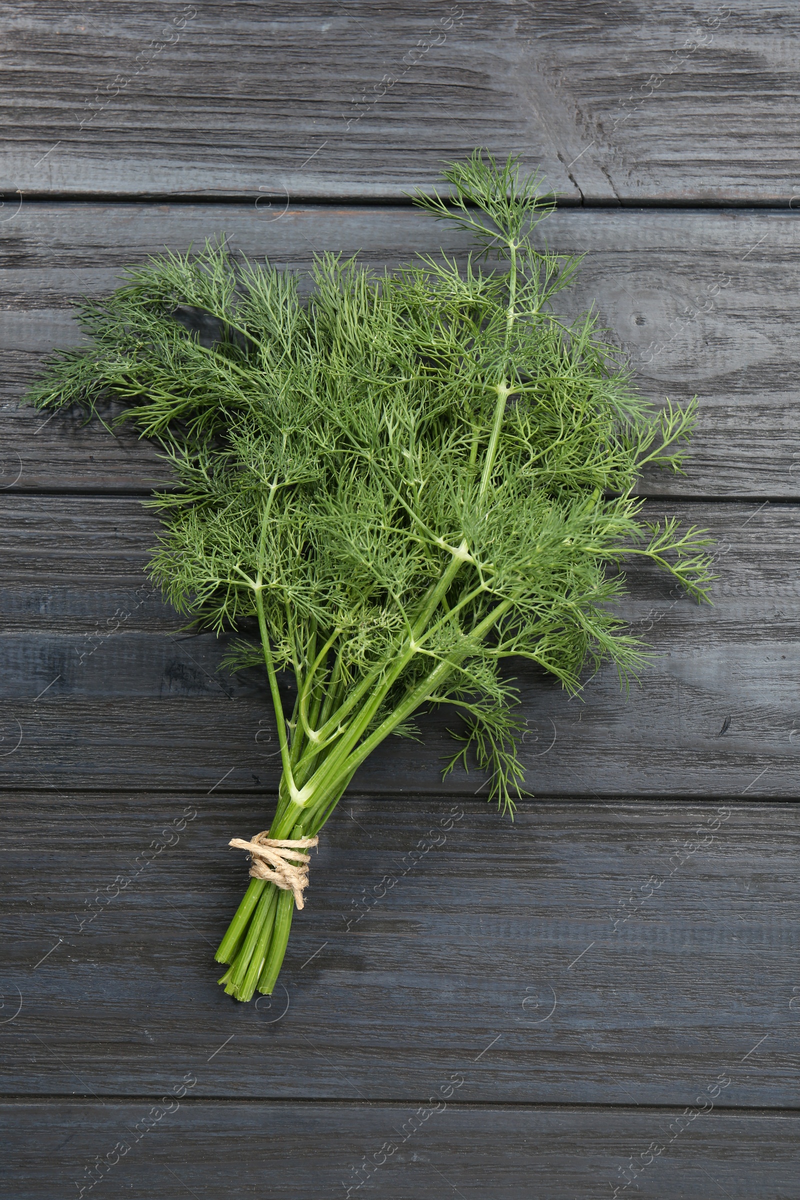 Photo of Bunch of fresh green dill on grey wooden table, top view