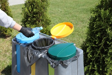 Photo of Woman throwing plastic bottle in bin outdoors, closeup. Recycling concept