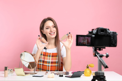 Photo of Beauty blogger filming make up tutorial on pink background