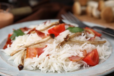 Photo of Delicious rice with bacon, mushrooms and tomatoes on table, closeup