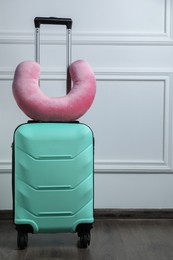 Pink travel pillow on turquoise suitcase indoors