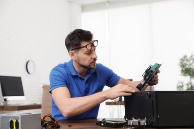 Male technician repairing computer at table indoors