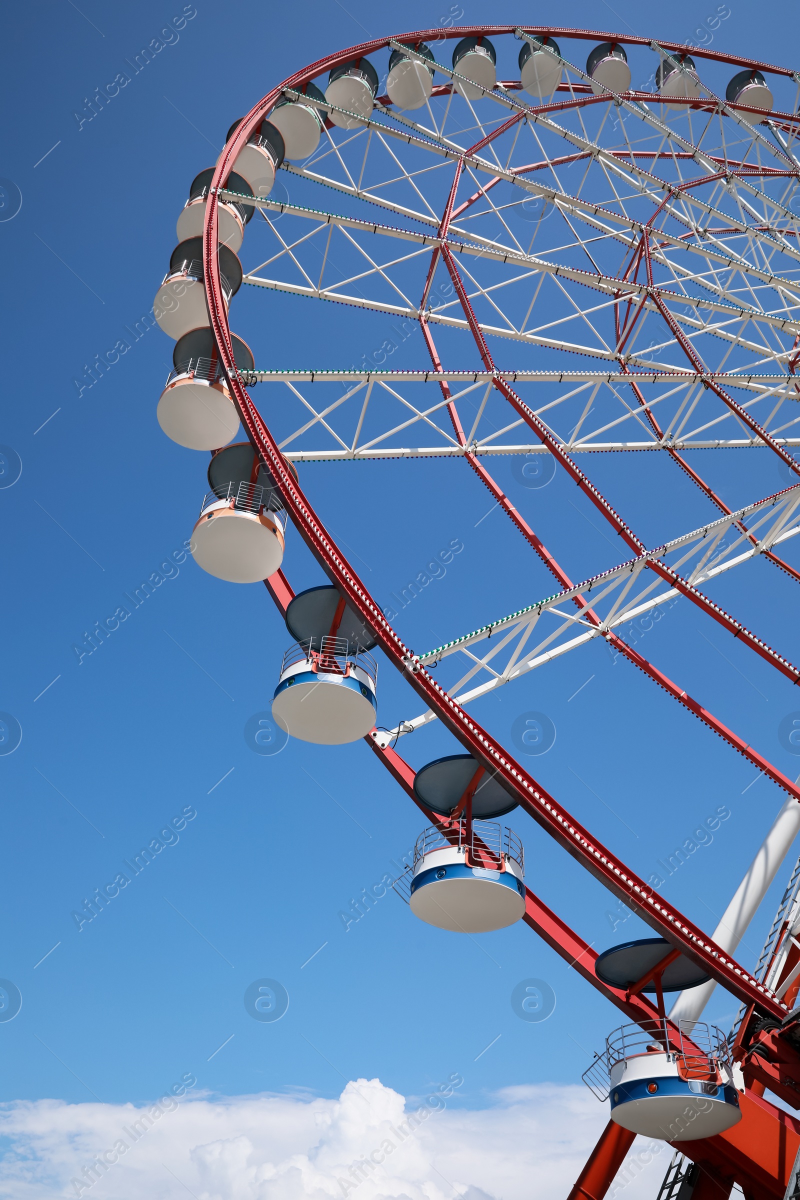 Photo of Beautiful large Ferris wheel against blue sky, low angle view