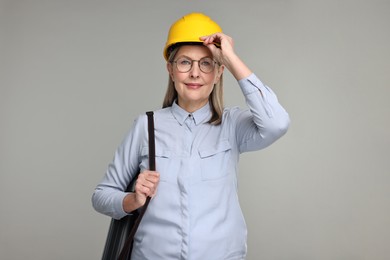 Photo of Architect in hard hat with tube on grey background