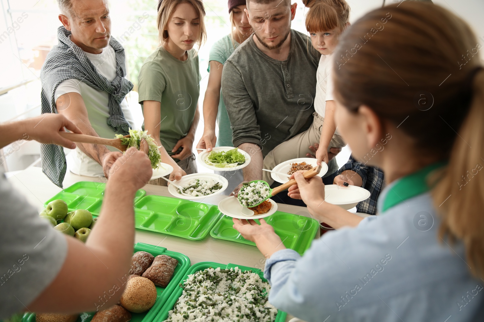 Photo of Volunteers serving food for poor people indoors