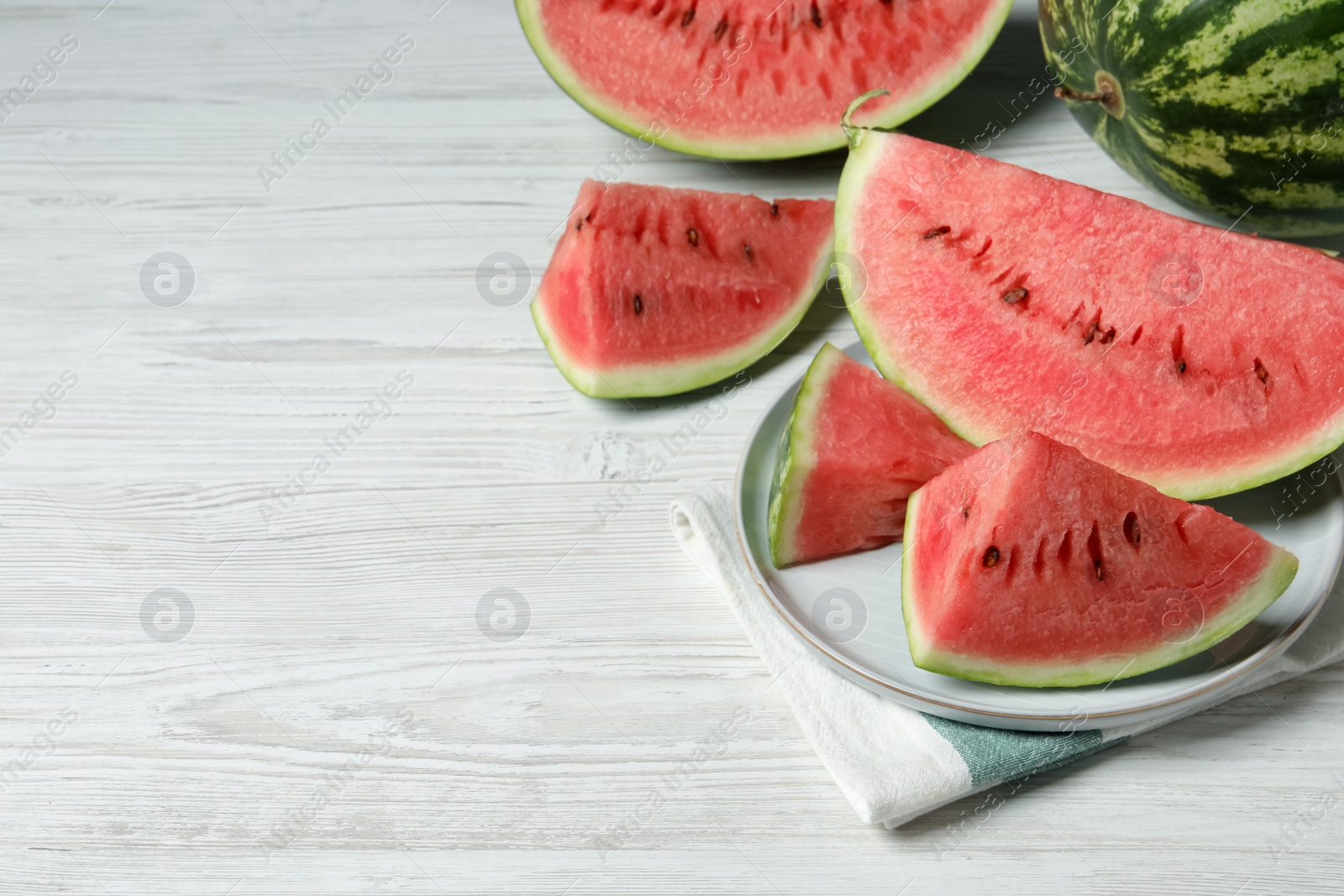 Photo of Tasty ripe watermelons on white wooden table, space for text