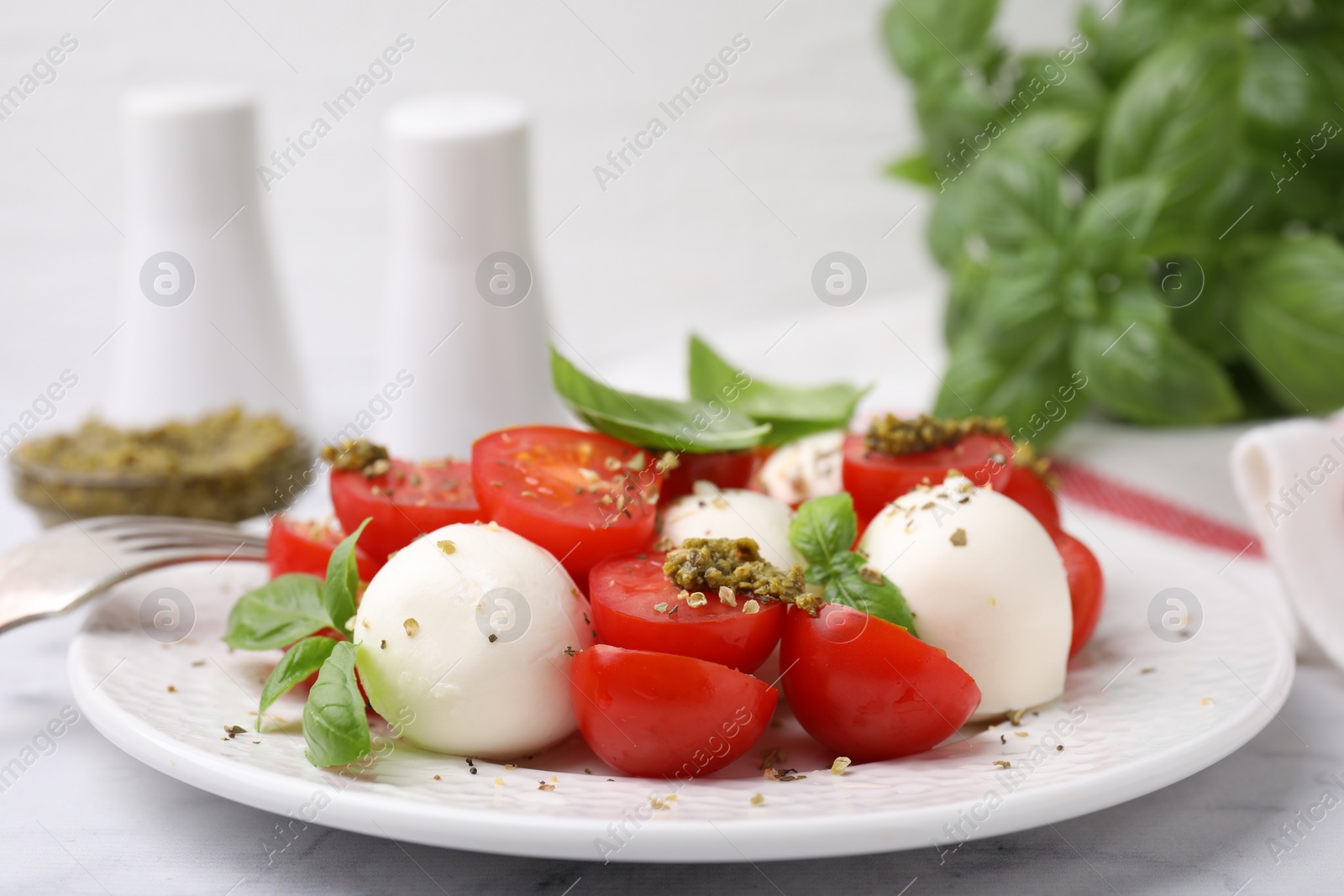 Photo of Tasty salad Caprese with tomatoes, mozzarella balls and basil served on table, closeup