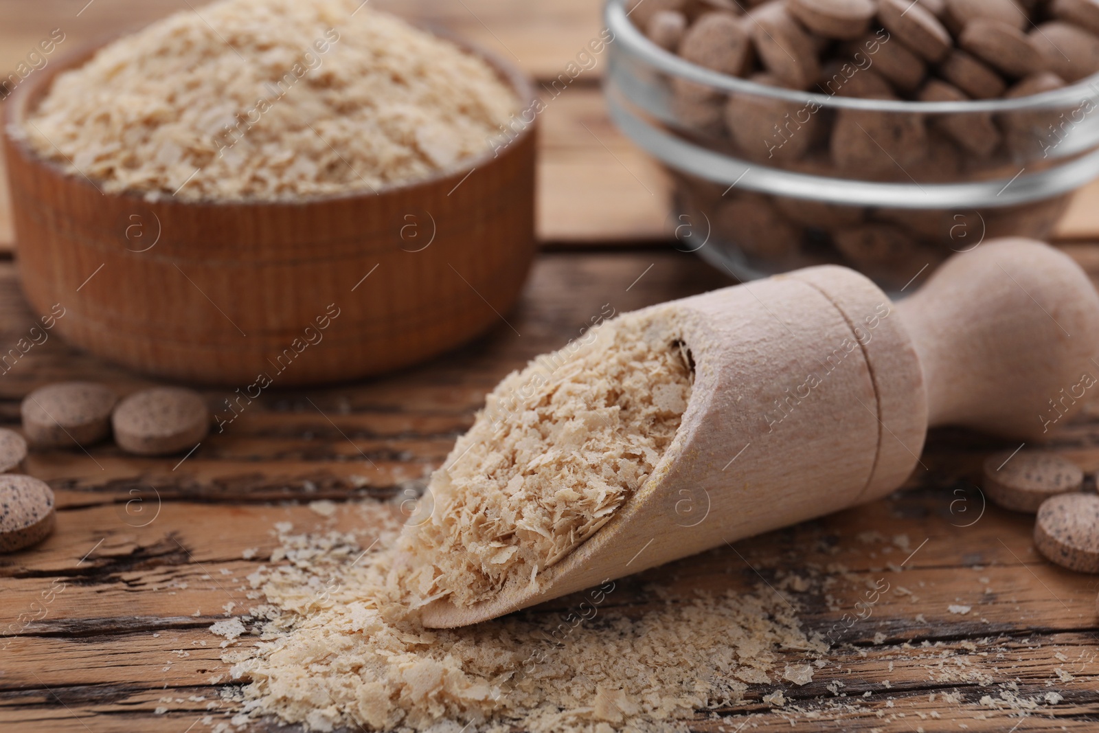 Photo of Scoop of brewer`s yeast flakes on wooden table, closeup. Space for text
