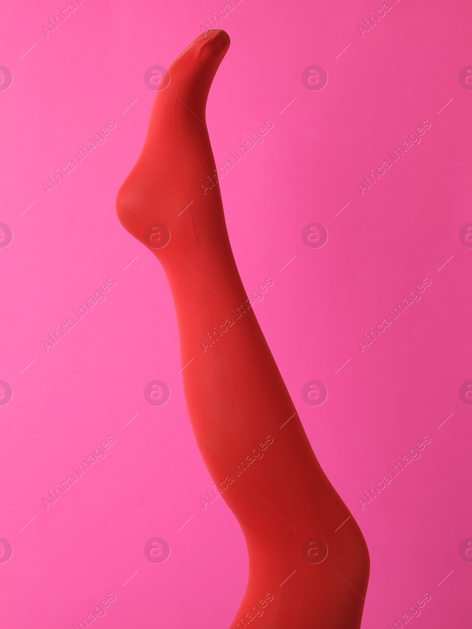 Photo of Leg mannequin in red tights on pink background