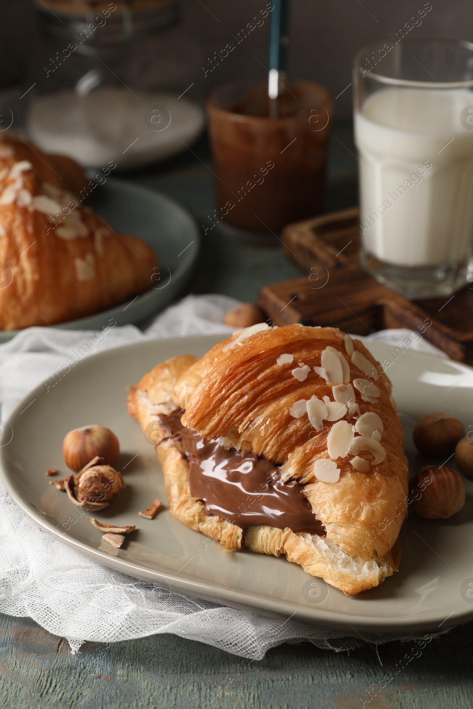 Photo of Delicious croissant with chocolate and nuts on table