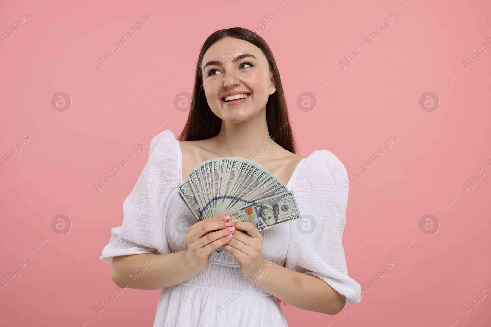 Photo of Happy woman with dollar banknotes on pink background