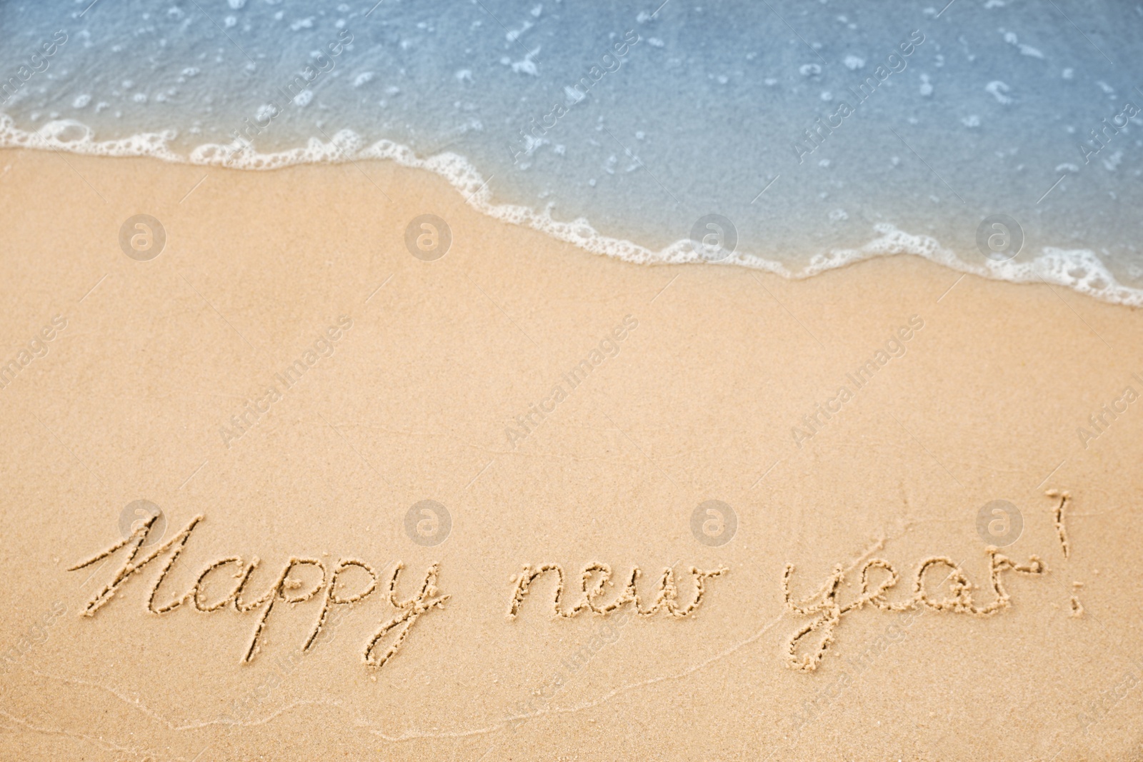 Photo of Sandy beach with text Happy New Year washed by sea, above view