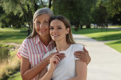 Photo of Family portrait of happy mother and daughter in park. Space for text