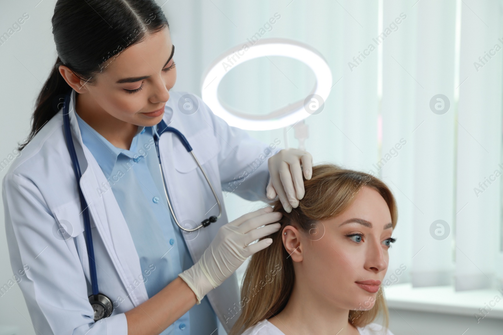 Photo of Young woman visiting trichologist in light clinic