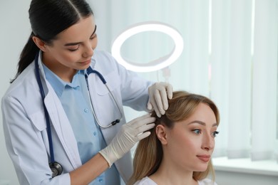 Photo of Young woman visiting trichologist in light clinic