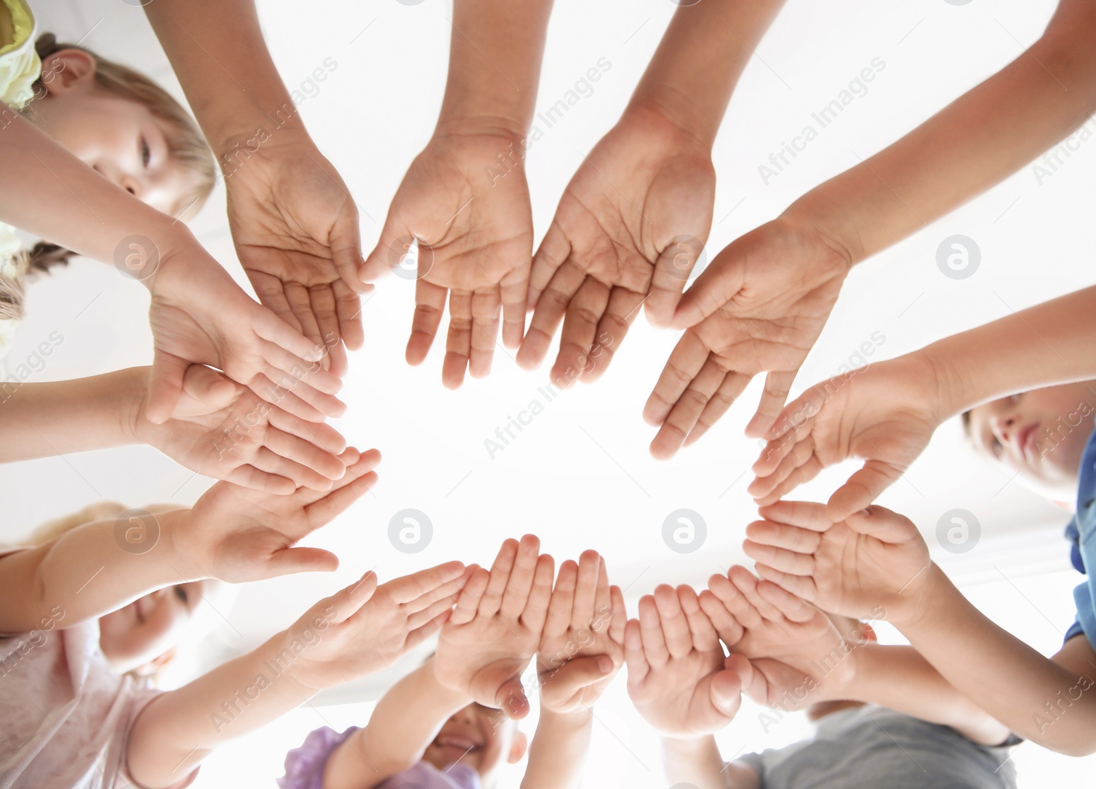 Photo of Little children putting their hands together indoors, view from below. Unity concept