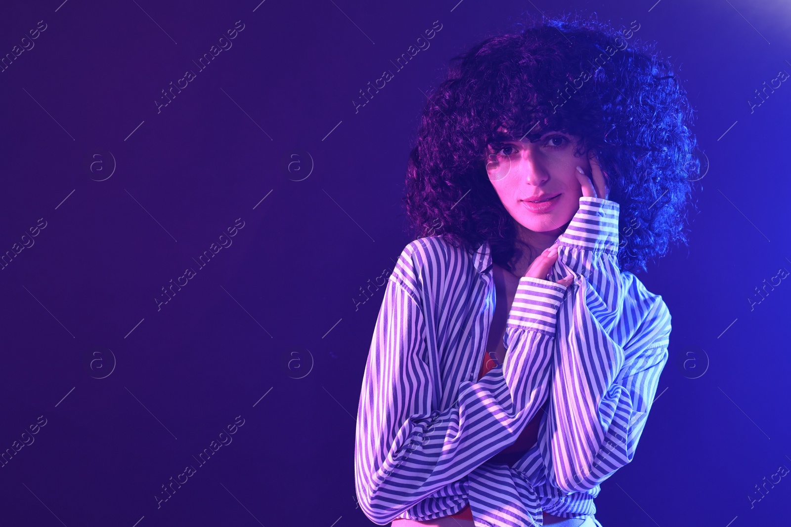 Photo of Beautiful young woman posing on color background in neon lights. Space for text