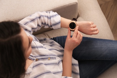 Photo of Young woman using smart watch at home, top view