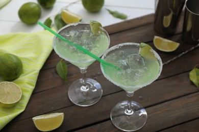 Photo of Delicious Margarita cocktail in glasses and lime on wooden table, closeup