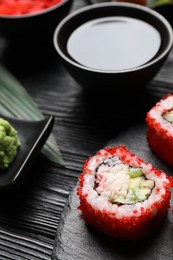 Photo of Tasty sushi rolls and soy sauce on black wooden table