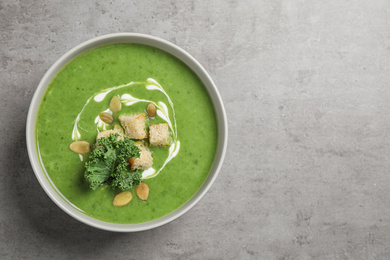 Tasty kale soup with croutons on grey table, top view. Space for text