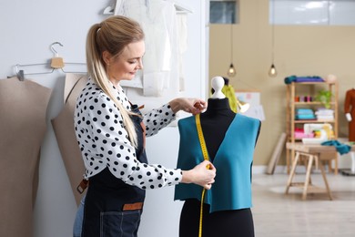 Dressmaker with measuring tape working in atelier