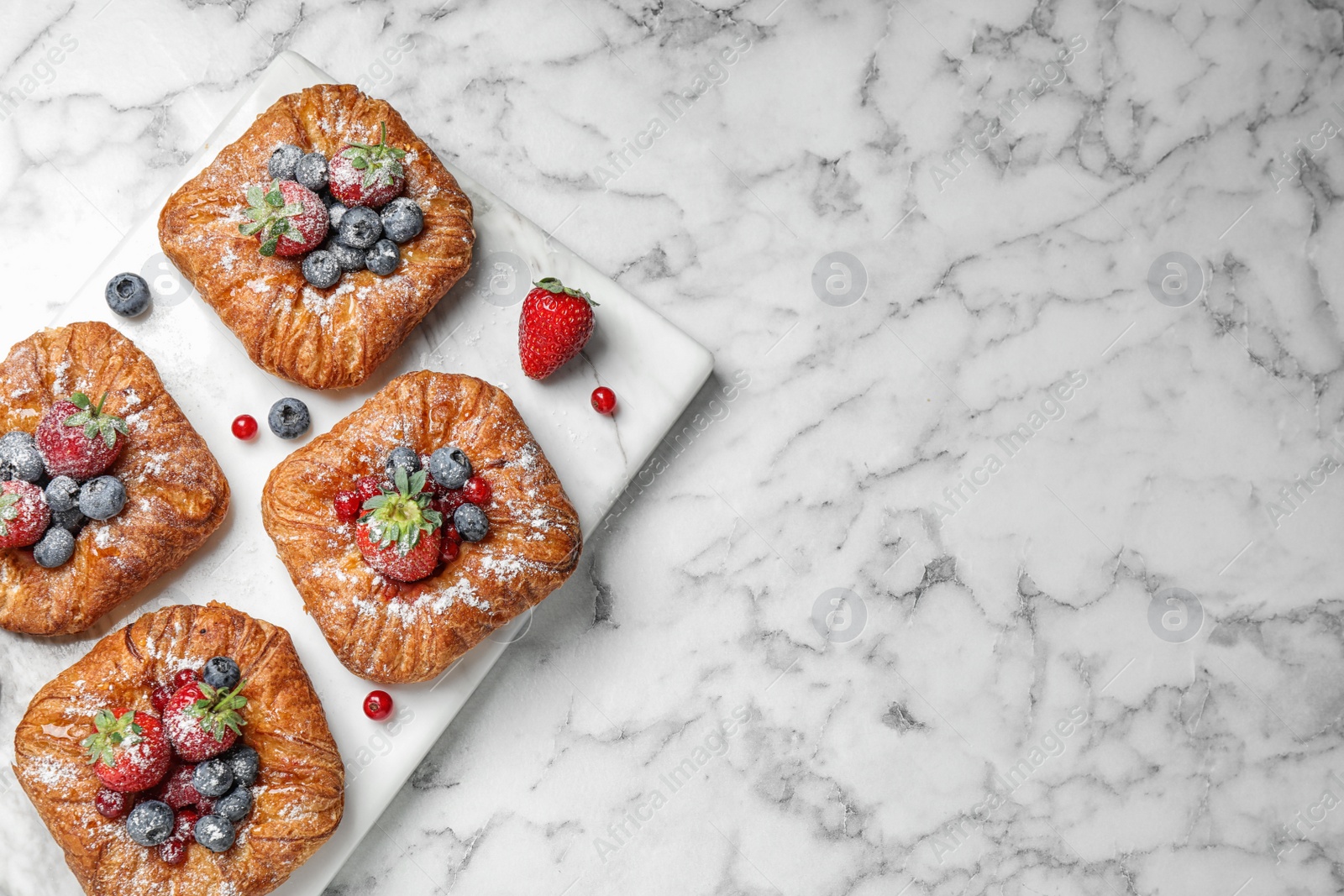 Photo of Fresh delicious puff pastry with sweet berries on white marble table, top view. Space for text