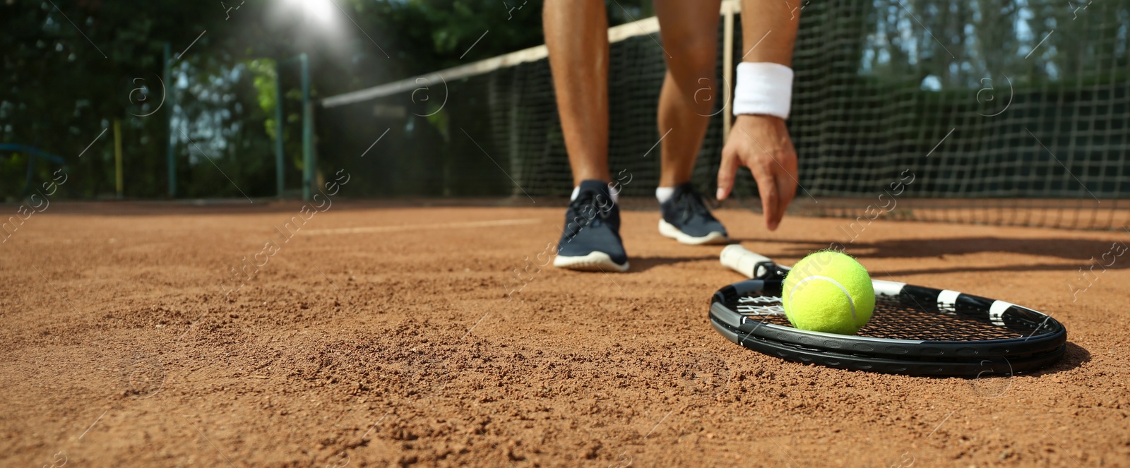 Image of Sportsman playing tennis at court on sunny day, closeup. Banner design with space for text