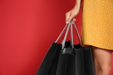 Young woman with shopping bags on red background, space for text. Black Friday Sale