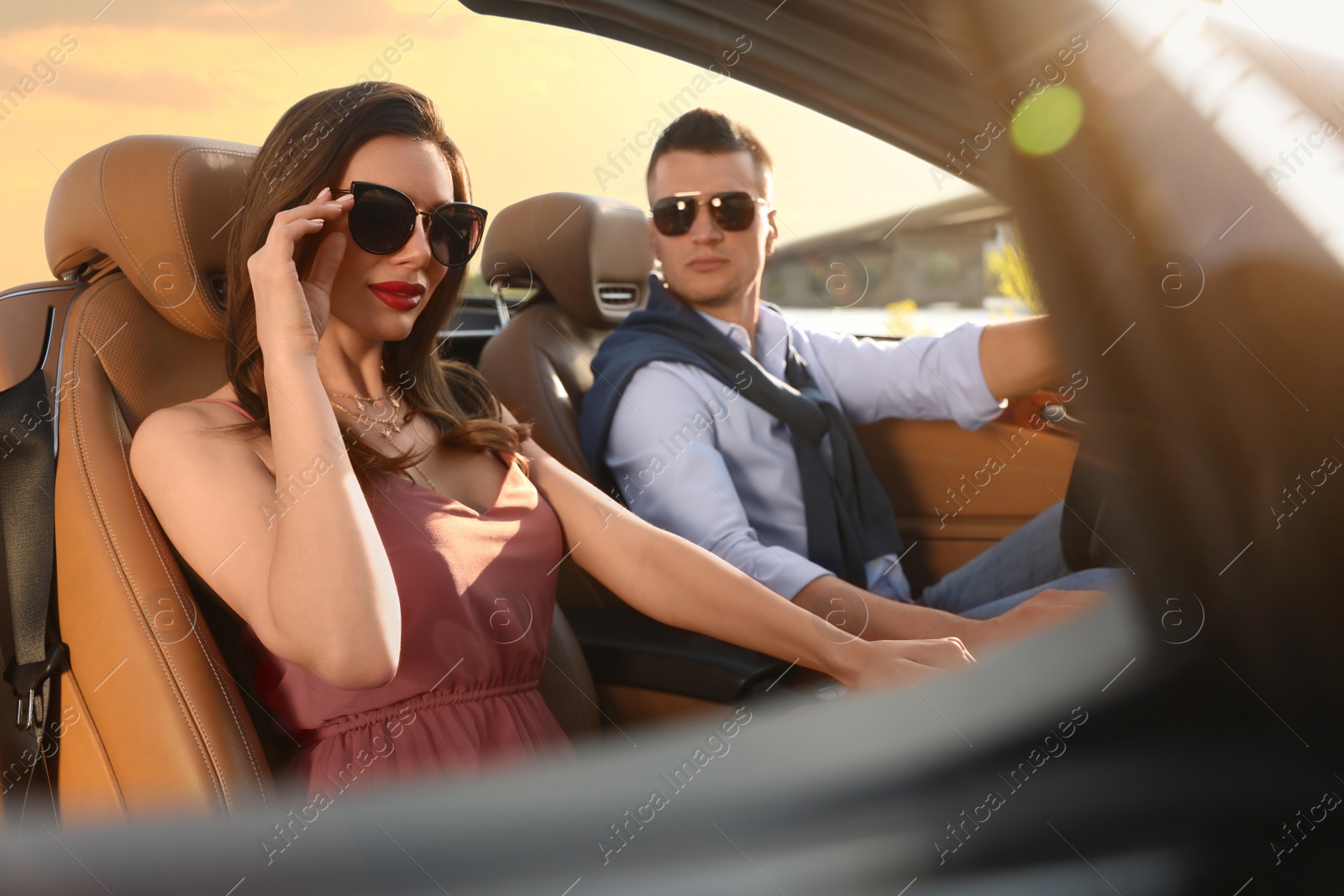 Photo of Stylish couple driving luxury convertible car outdoors