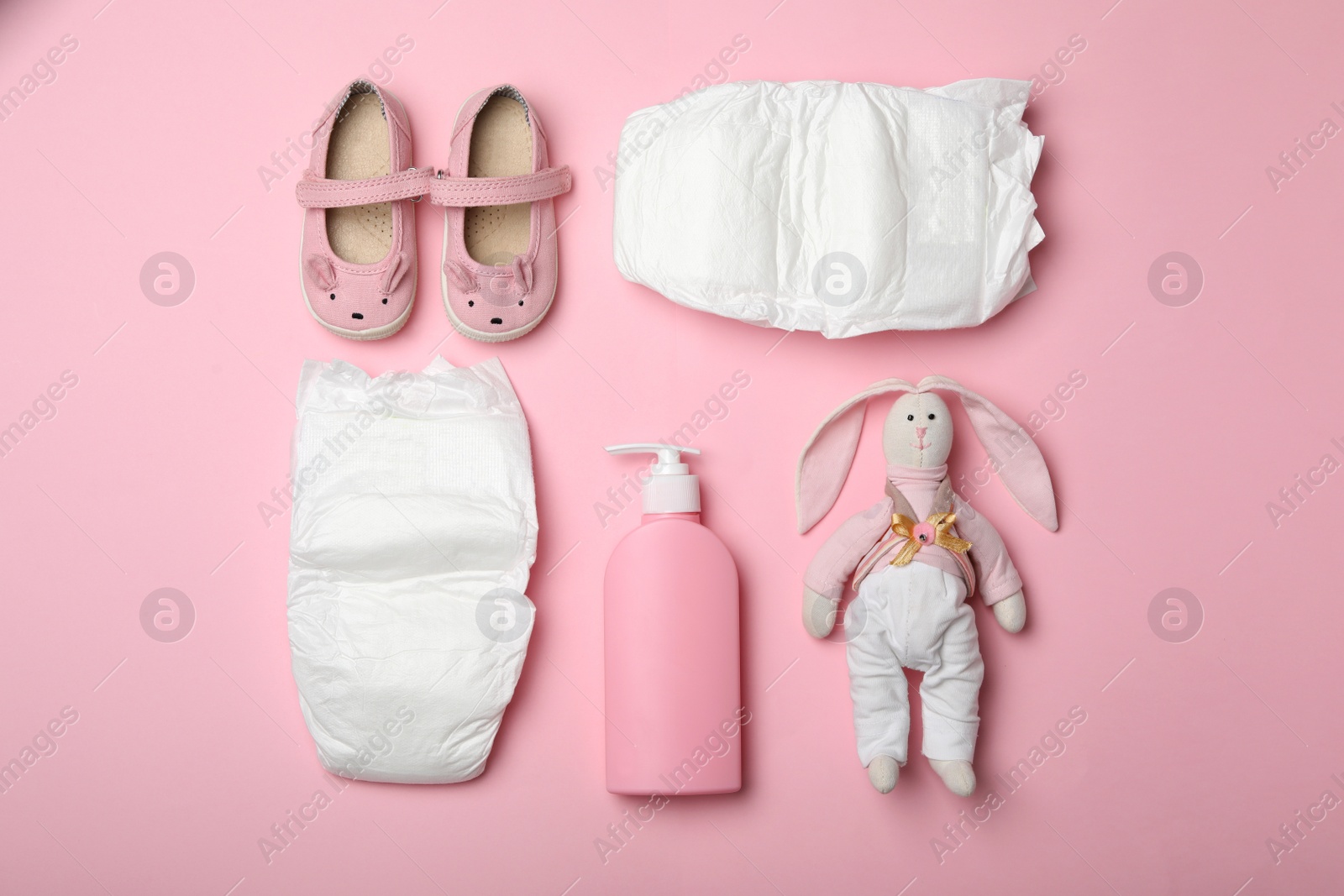 Photo of Diapers and baby accessories on pink background, flat lay