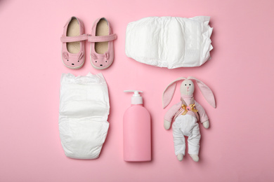 Photo of Diapers and baby accessories on pink background, flat lay