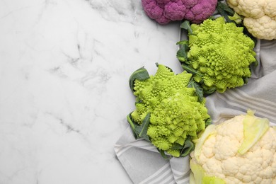 Different fresh cabbages on white marble table, flat lay. Space for text