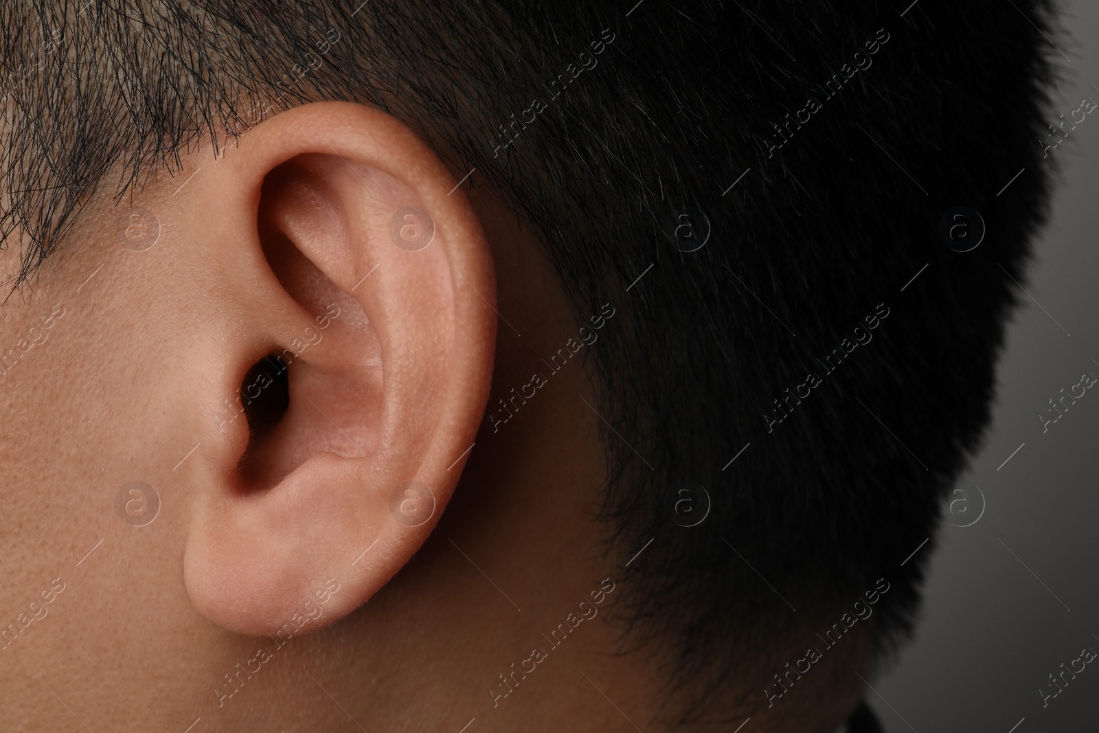 Photo of Man on grey background, closeup of ear