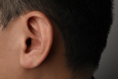 Man on grey background, closeup of ear