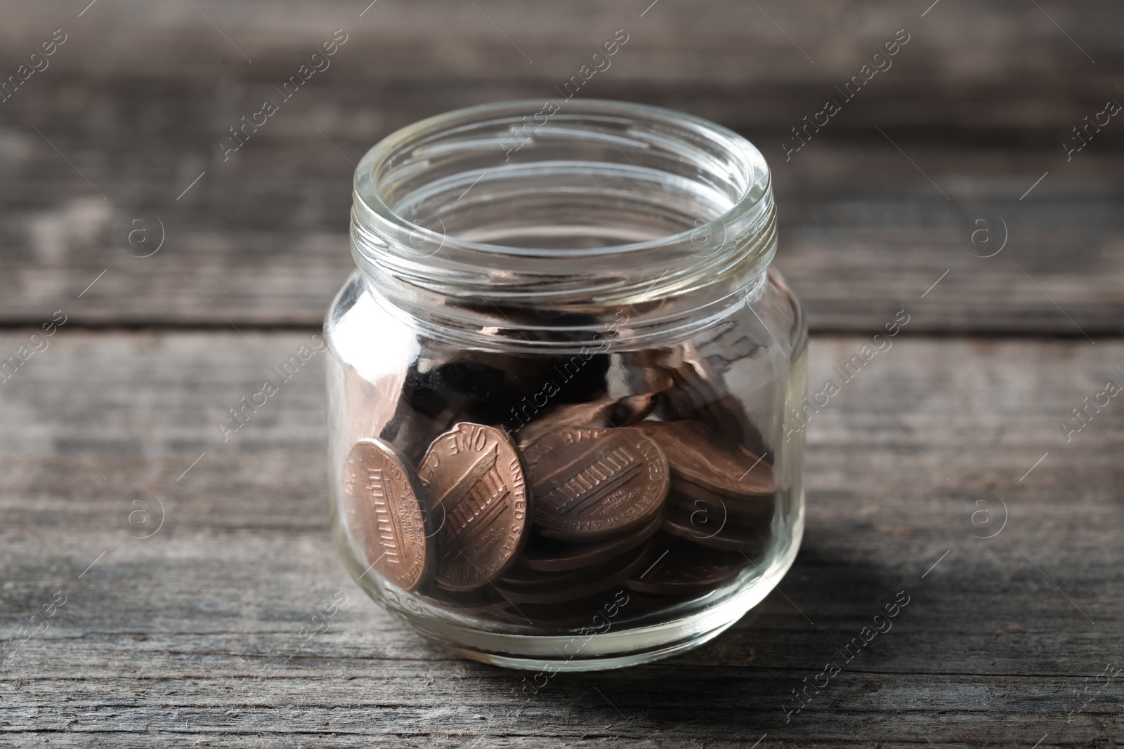 Photo of Glass jar with coins on wooden table, closeup