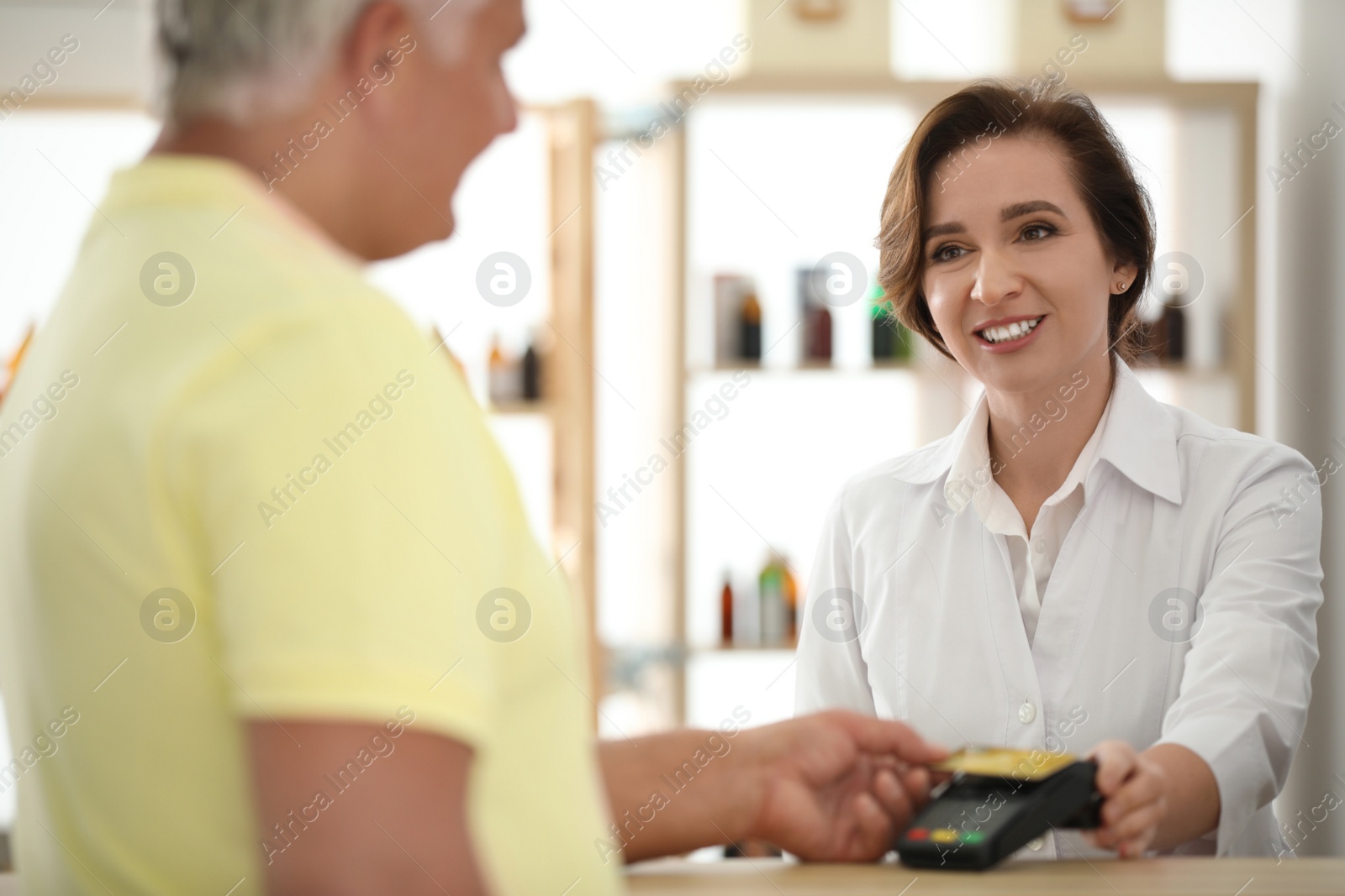 Photo of Customer using terminal for contactless payment with credit card in pharmacy