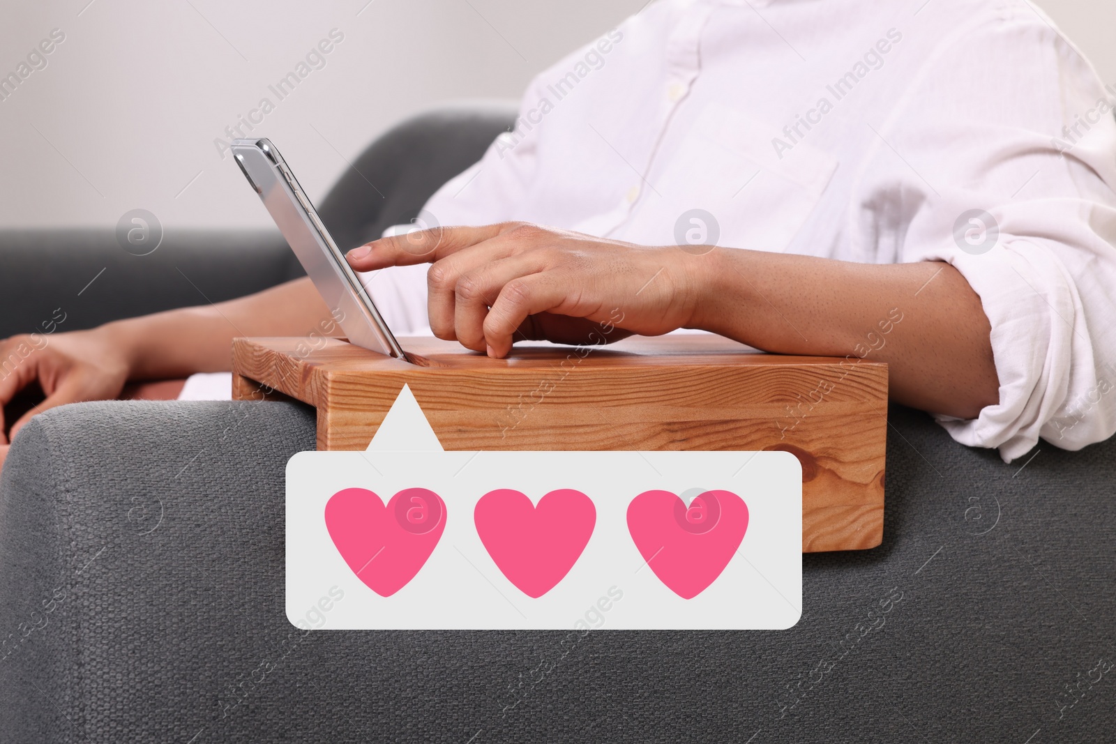 Image of Long distance love. Man sending or receiving text message on sofa, closeup. Speech bubble with hearts near device