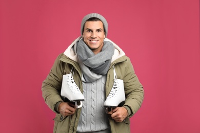 Photo of Happy man with ice skates on pink background