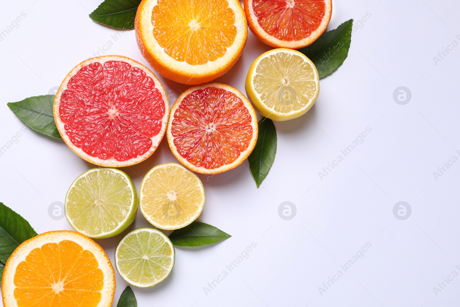 Photo of Fresh juicy citrus fruits with green leaves on white background, flat lay. Space for text