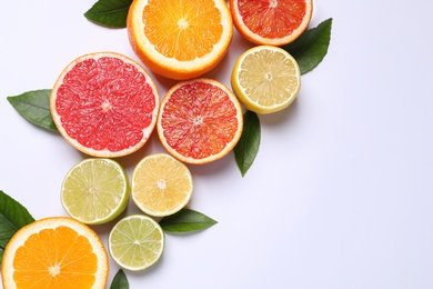 Photo of Fresh juicy citrus fruits with green leaves on white background, flat lay. Space for text