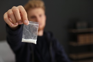 Photo of Criminal holding plastic bag with drug indoors, space for text